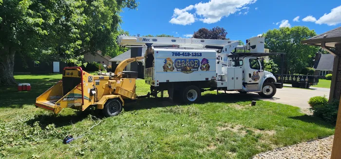 Grace Tree Service crew chipping branches with a wood chipper and bucket truck
